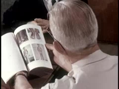 A person flipping through pages of a photographic guide detailing various subjects