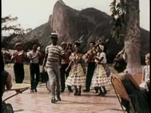Traditional dancers performing outdoors with musicians playing instruments nearby.