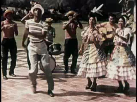 Traditional dancers in colorful costumes performing outdoors with live musicians.
