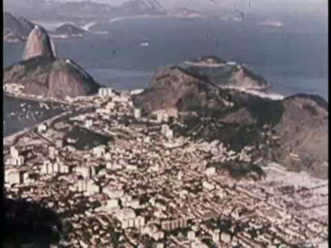 High-angle aerial view of a dense coastal city and harbor landscape.