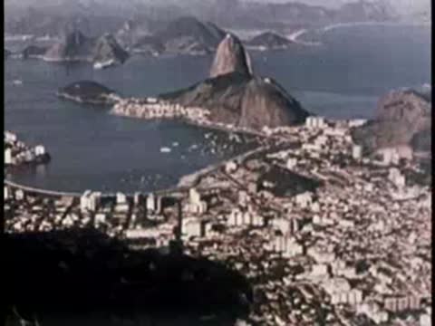 Wide aerial view of a coastal city, beaches, and harbor with boats.
