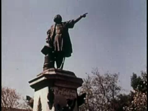 Statue of a historical figure pointing forward atop a stone pedestal.