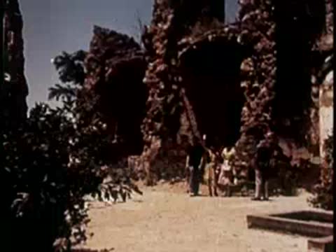 People walking among historic stone ruins under bright daylight.