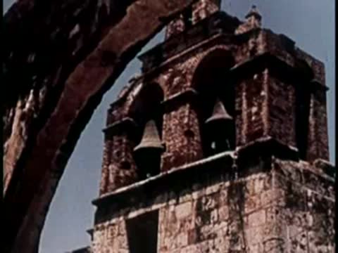 Historic stone bell tower with multiple arches and hanging bells.