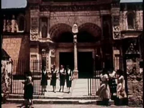 People gathered outside the entrance of a historic stone building.