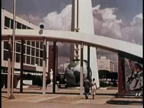 Modern urban plaza with a large metallic globe sculpture and buildings.