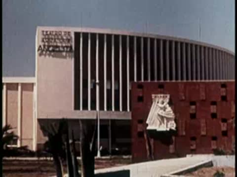Modern building facade with vertical slats and a white sculptural relief.