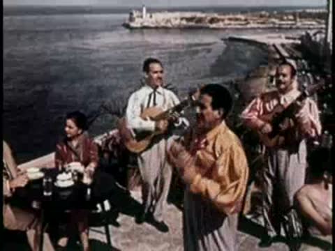 Men in white shirts playing guitars and singing near water.