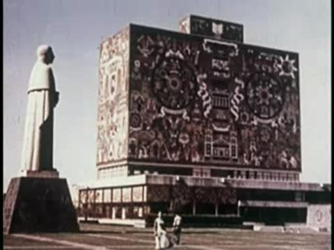 Large modern building with mural facade and a statue in foreground.