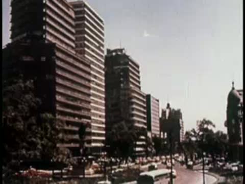 Urban street scene with tall modern buildings and moving traffic.