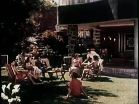 People relaxing on lounge chairs in a sunny garden courtyard.