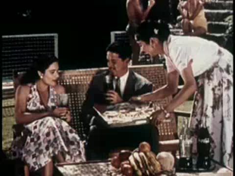 Couple seated on outdoor seating while a woman serves food.