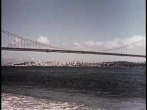 A bridge spanning over water with a city skyline, mid-century era.