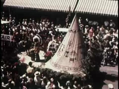 A large crowd gathered around a tent in a street, 1950s.
