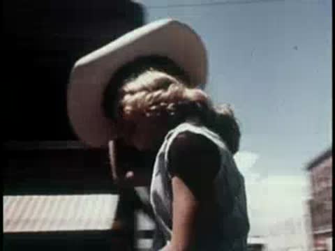 A young girl riding a horse in a parade, 1950s style.