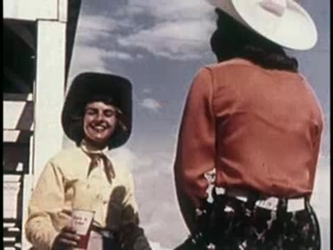 Two women in Western attire standing and talking in an arena, 1950s.