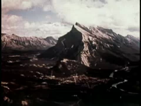 dramatic view of a large snow-capped mountain peak towering over a river valley
