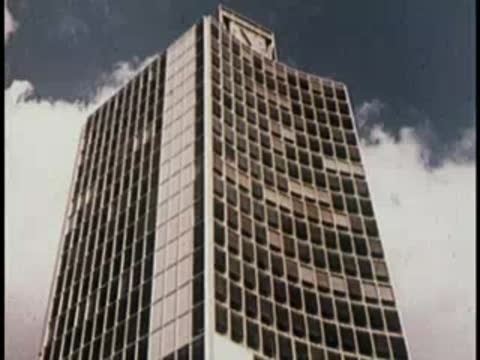 Modern skyscraper with a grid facade of dark windows and white frames.