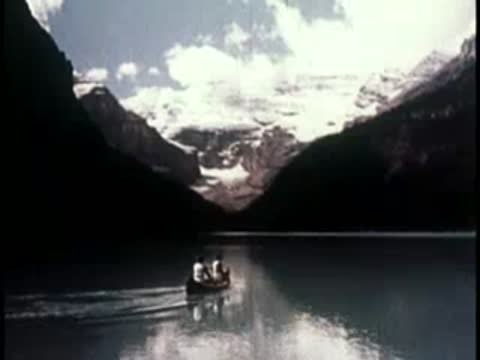 scenic lake with a canoe in the foreground and towering dark mountains behind