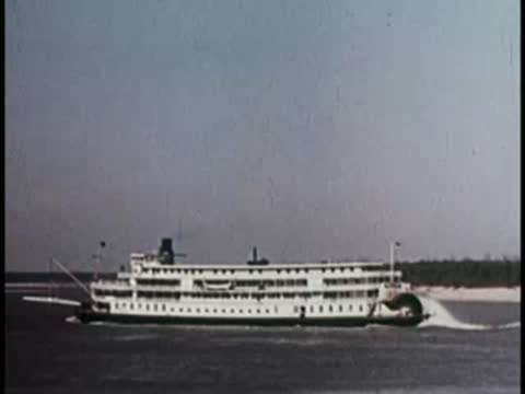 a paddle steamer boat cruising on a calm river or lake near a shore