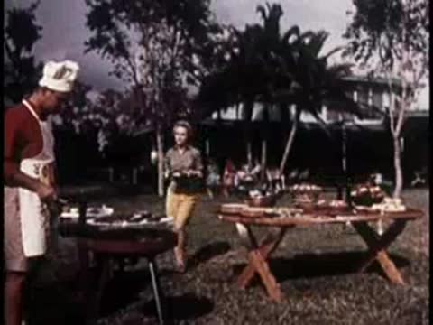 people preparing food at an outdoor barbecue setup near a resort building