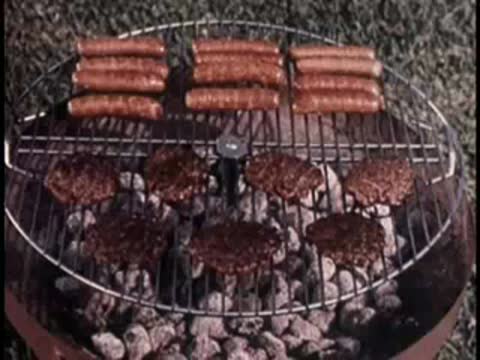 close-up of hot dogs and hamburgers grilling on a charcoal grill outdoors