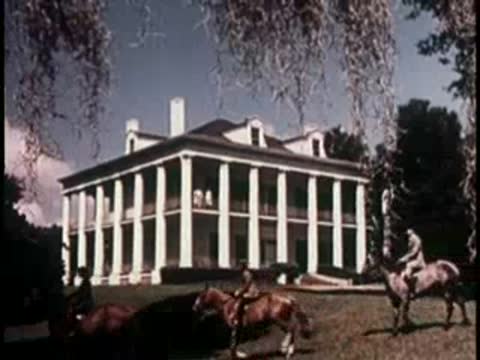 large white colonial-style mansion with tall columns and horses on the lawn