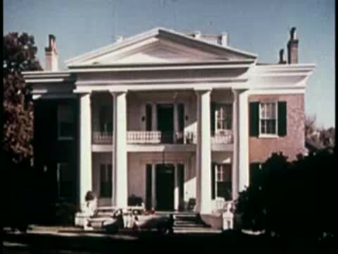 front facade of a large historic white colonial mansion with a grand porch
