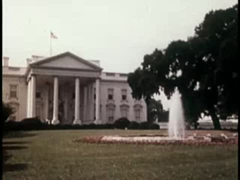 close-up view of the white house with large trees and a fountain in the foreground