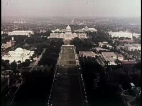 aerial view looking down a long, tree-lined avenue toward a capitol building dome